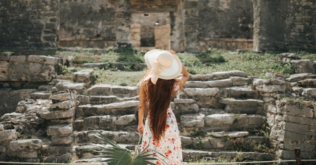 A woman in a summer dress and hat explores the ancient Mayan ruins in Tulum, Mexico.