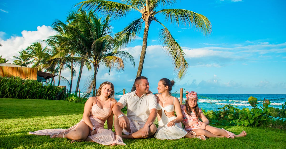 Family enjoying a sunny day on lush green lawn by the ocean with palm trees.